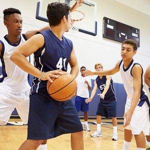 Male High School Basketball Team Playing Game In Gymnasium
