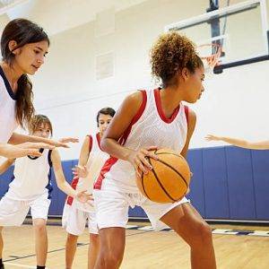 Female High School Basketball Team Playing Game In Gymnasium